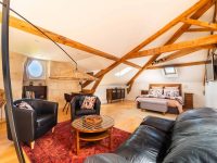Vue intérieure de la Suite l’Estuaire avec lit queen-size, coin salon, poutres apparentes et décoration raffinée au Château Papounan, chambre d’hôtes de charme à Saint-Estèphe, Médoc.