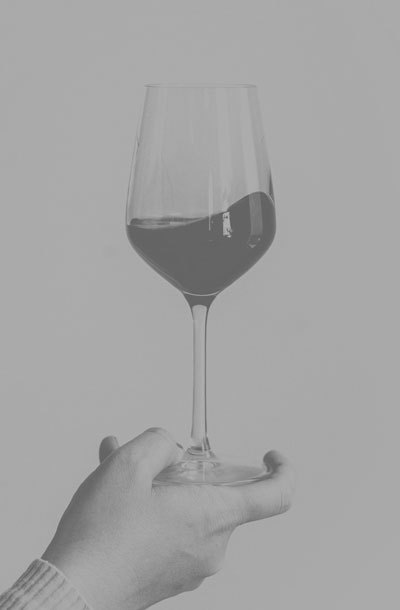 Main qui soulève un verre de vin rouge