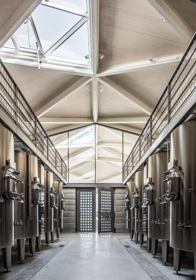 A spacious hallway with high ceilings and skylights, lined with tall, metal shelves and bright, natural light.